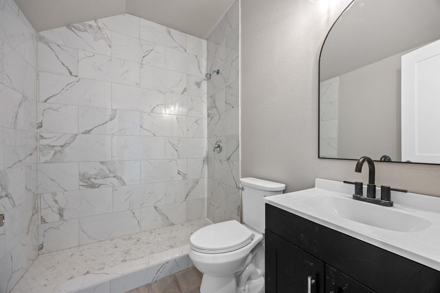Full bath featuring a tile shower, toilet, and vanity Full bath featuring a tile shower, toilet, and vanity
