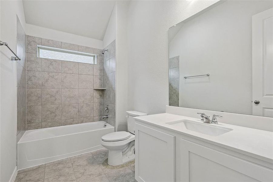 Full bathroom with tile flooring, toilet, oversized vanity, and tiled shower / bath