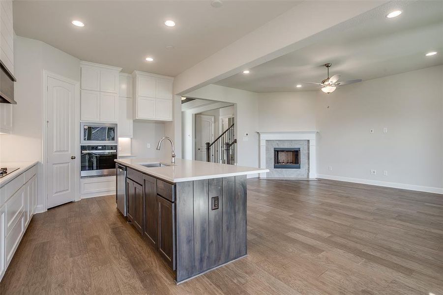 Kitchen with a kitchen island with sink, dark brown cabinets, stainless steel appliances, sink, and light wood-type flooring