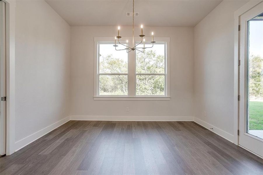 Unfurnished dining area with a wealth of natural light, dark hardwood / wood-style floors, and a chandelier