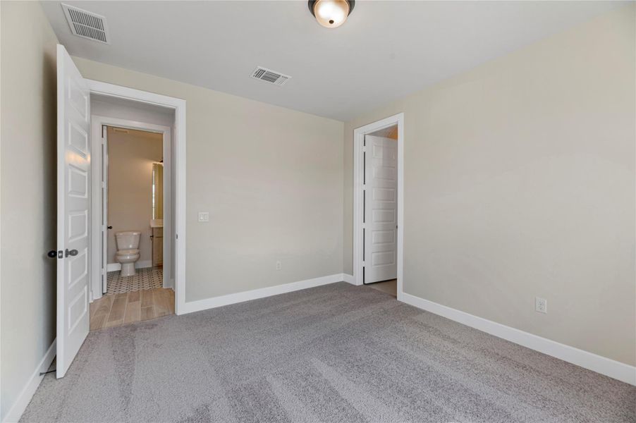 Unfurnished bedroom with light carpet and baseboards