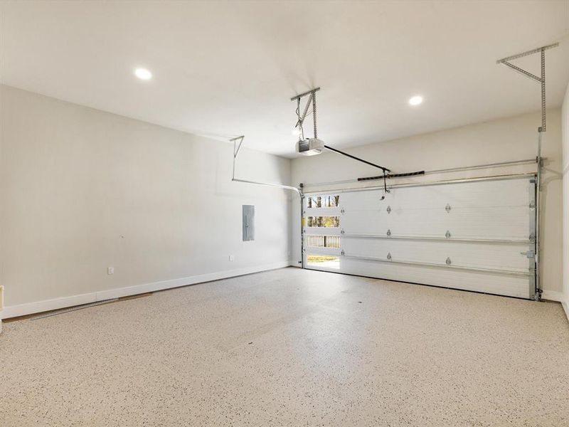 Garage with electric panel, recessed lighting, and a garage door opener