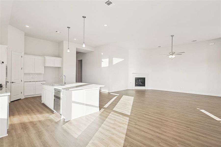 Kitchen with white cabinetry, light hardwood / wood-style floors, a towering ceiling, and sink