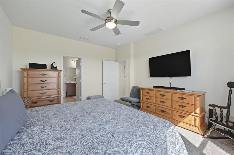 Bedroom with light carpet, a ceiling fan, and ensuite bath Bedroom with light carpet, a ceiling fan, and ensuite bath