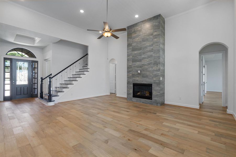 Spacious interior featuring wood-finish flooring, a contemporary fireplace with stacked stone surround, and an elegant staircase with wrought iron balusters