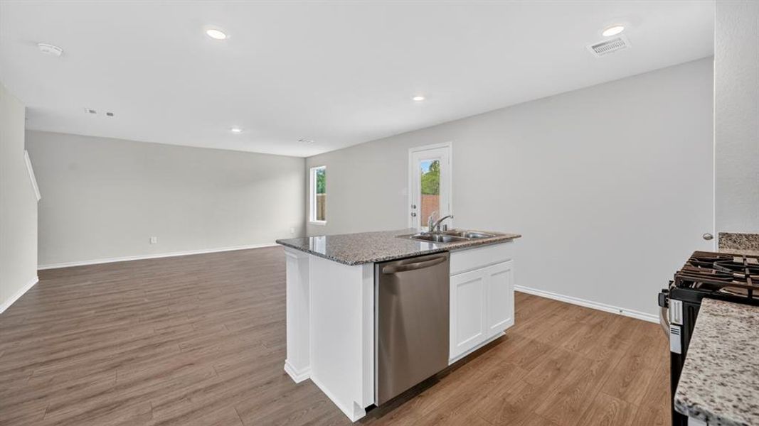 Open-concept kitchen and living area featuring wood-finish flooring, recessed lighting, and light-toned walls