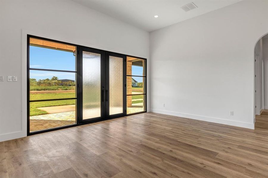 Dining room with wood finished floors, arched walkways, and recessed lighting