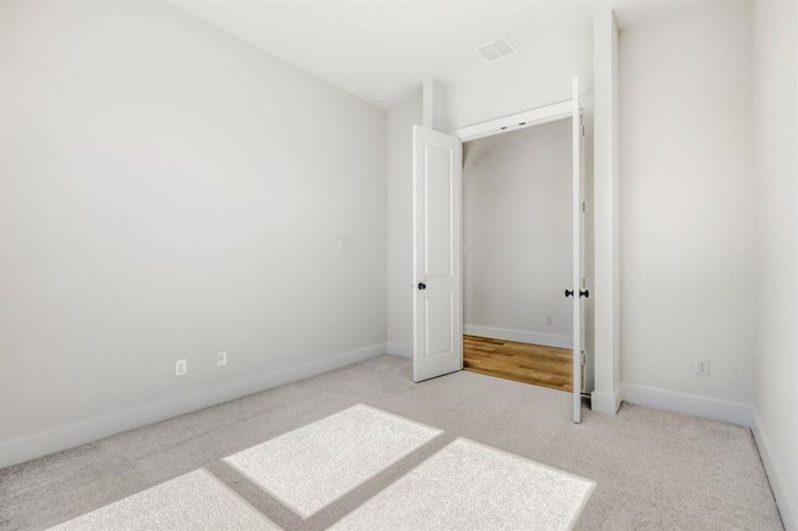 Unfurnished bedroom with light carpet and baseboards
