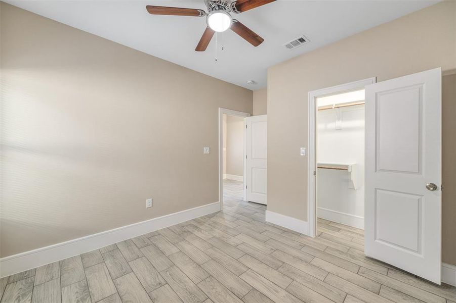 Unfurnished bedroom featuring ceiling fan, light hardwood / wood-style floors, a spacious closet, and a closet