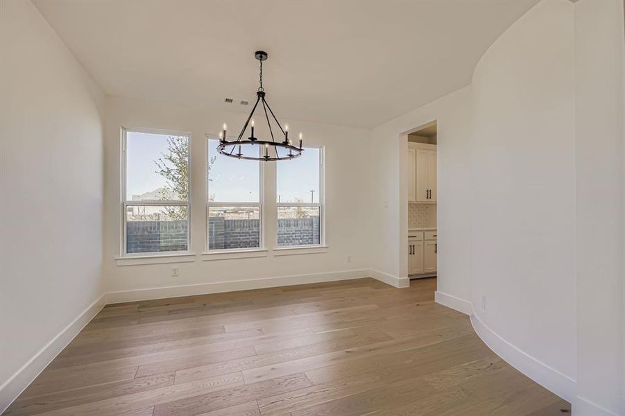 Unfurnished dining area with light wood-type flooring and a chandelier