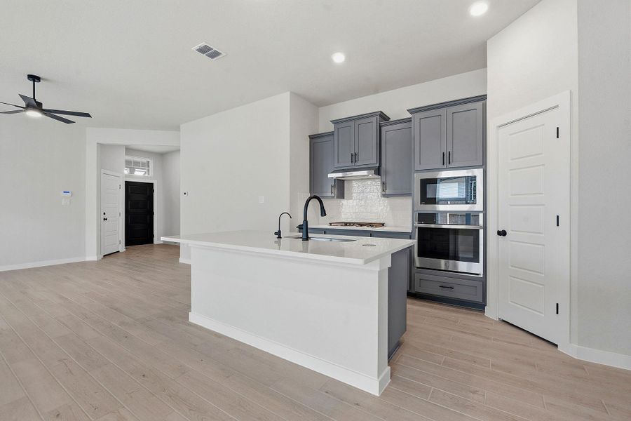 A contemporary kitchen island with a sleek faucet overlooks bright, open-concept living space.