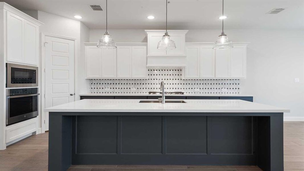 Kitchen with white cabinets, sink, decorative backsplash, an island with sink, and stainless steel appliances