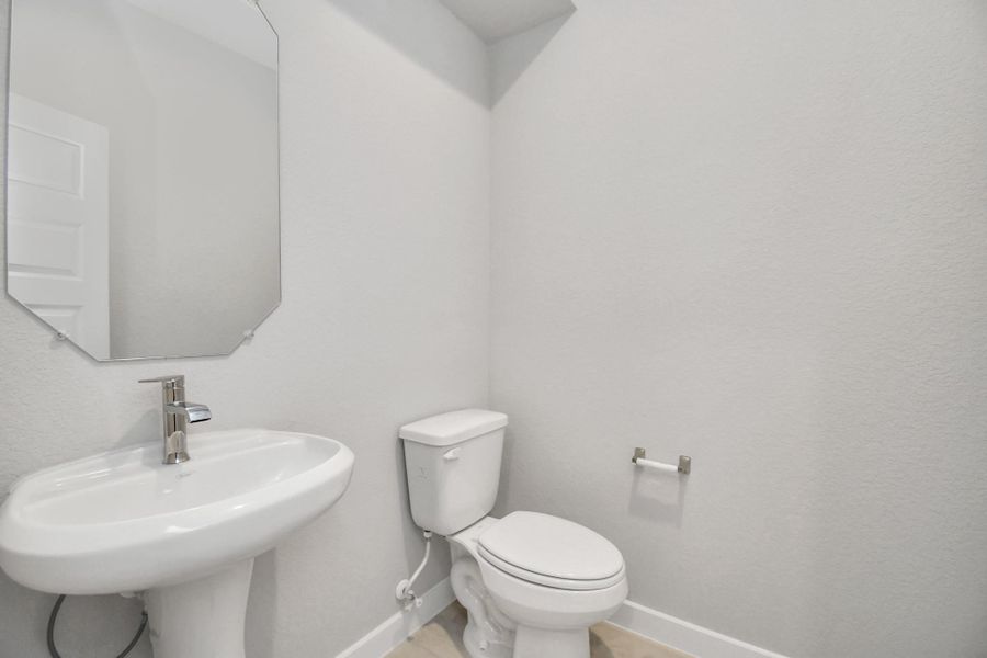 This half bathroom features a stylish pedestal sink, modern hardware, and bright recessed lighting, creating a sleek and inviting space. Sample photo of completed home with similar floor plan. Actual colors and selections may vary.