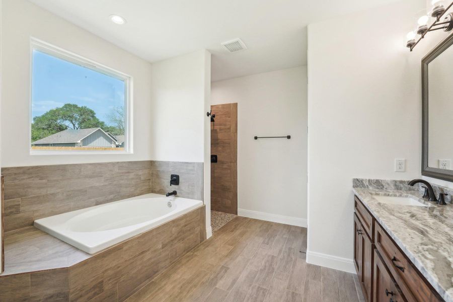 Full bathroom featuring a bath, vanity, baseboards, visible vents, and tiled shower Full bathroom featuring a bath, vanity, baseboards, visible vents, and tiled shower