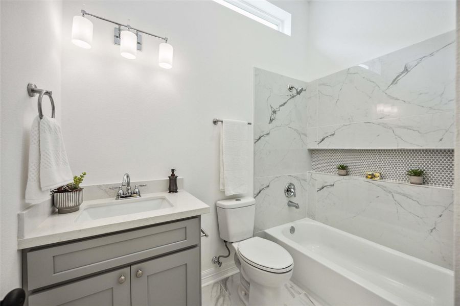 Features a clean tub/shower combo with modern tile work and a sleek vanity.
