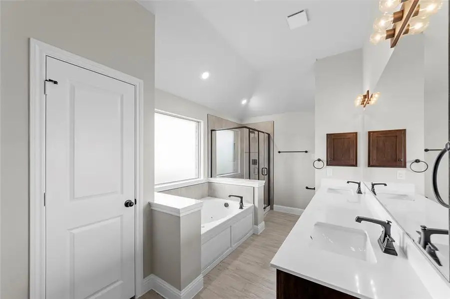 Full bath featuring a stall shower, a garden tub, double vanity, light wood-type flooring, and recessed lighting