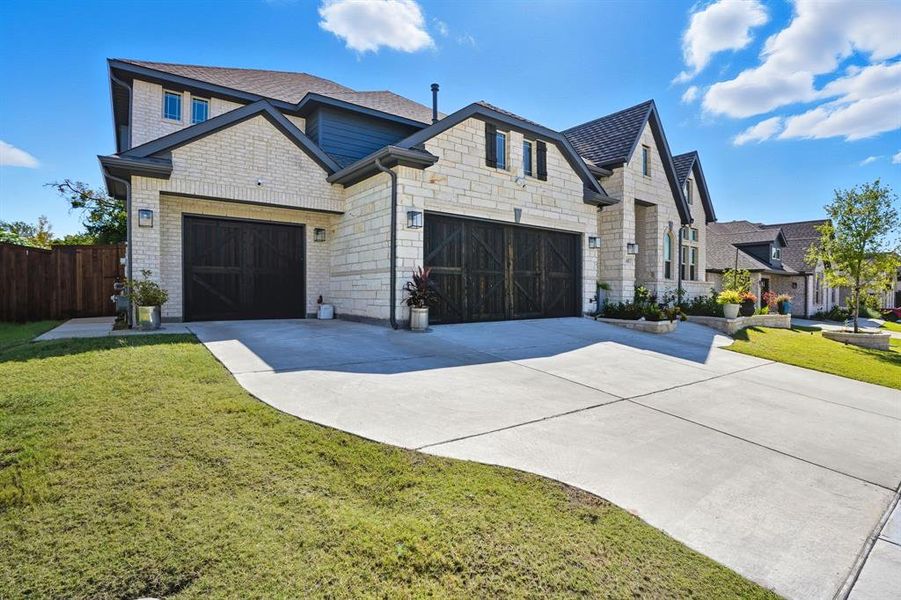 French country style house featuring driveway, an attached garage, and stone siding