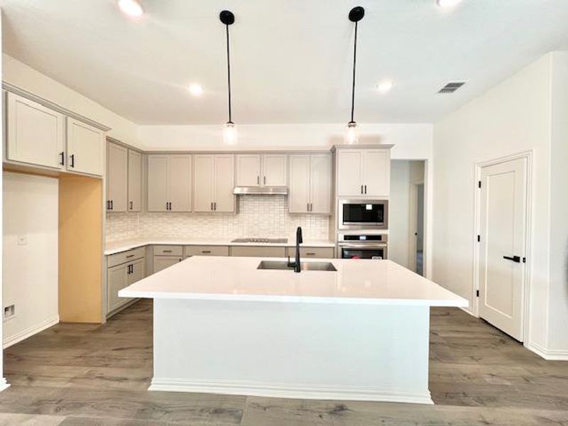 Kitchen with backsplash, built in microwave, visible vents, stainless steel oven, and a sink Kitchen with backsplash, built in microwave, visible vents, stainless steel oven, and a sink