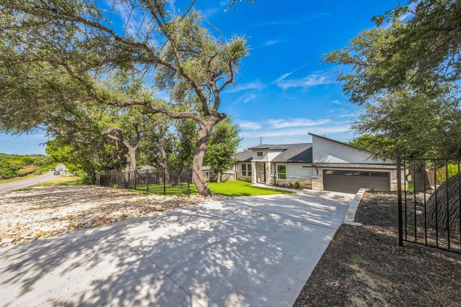 View of front of home with stone siding, driveway, stucco siding, and a garage