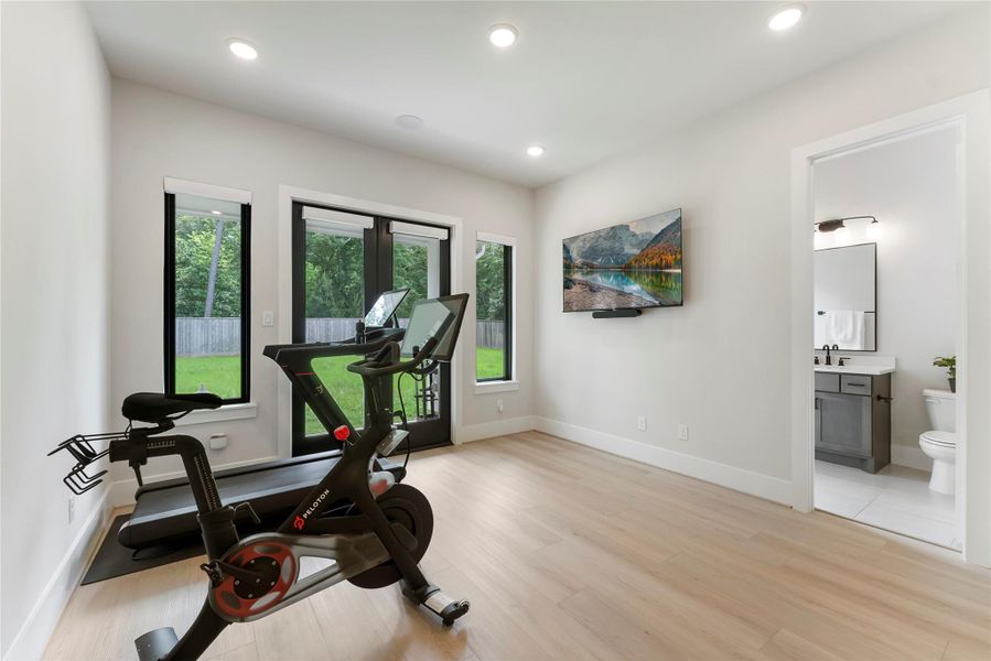 Gym/flex room offers excellent versatility with windows, plank flooring, and access to a full bath. It can function as a fitness room, studio, private office, or 6th bedroom.