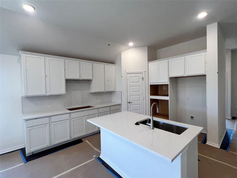 Kitchen featuring white cabinets, light stone counters, tasteful backsplash, a center island with sink, and recessed lighting