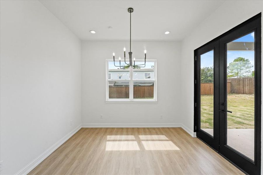 Dining area featuring recessed lighting, a contemporary chandelier, wood-finish flooring, a bright window, and double glass-paneled exterior doors