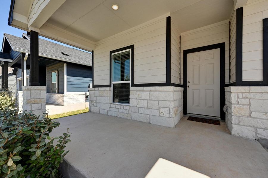 Entrance to property with a porch and stone siding