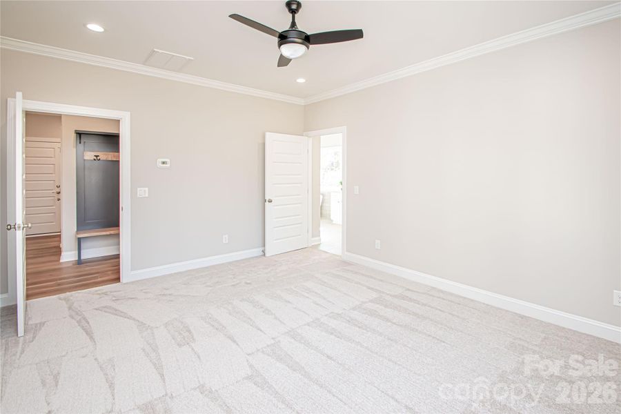 The large primary bedroom boasts recessed lighting, a sleek modern ceiling fan, plush carpet, and abundant windows that provide plenty of natural light.