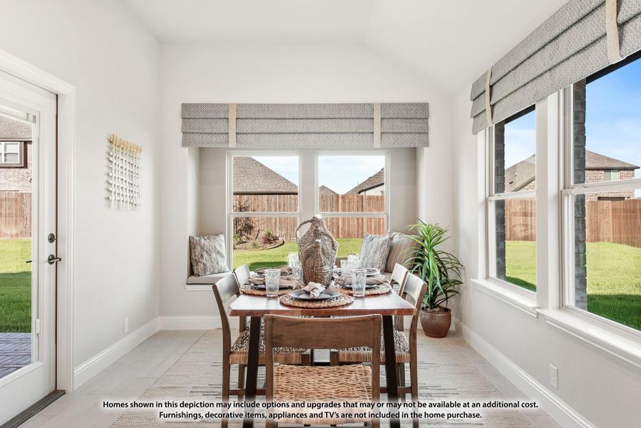 Bright breakfast nook with dining table, window seat, and large windows overlooking backyard