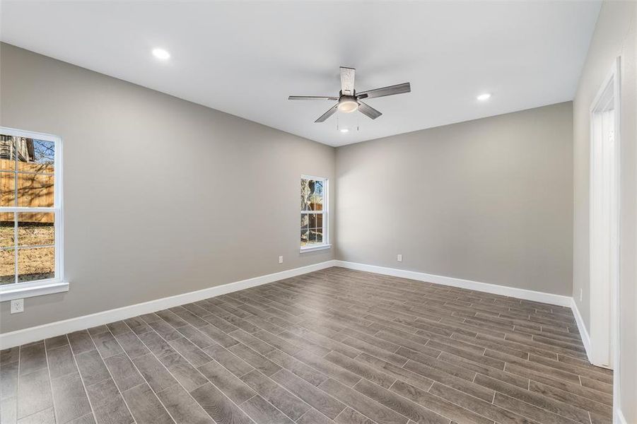 Empty room with ceiling fan and dark hardwood / wood-style flooring