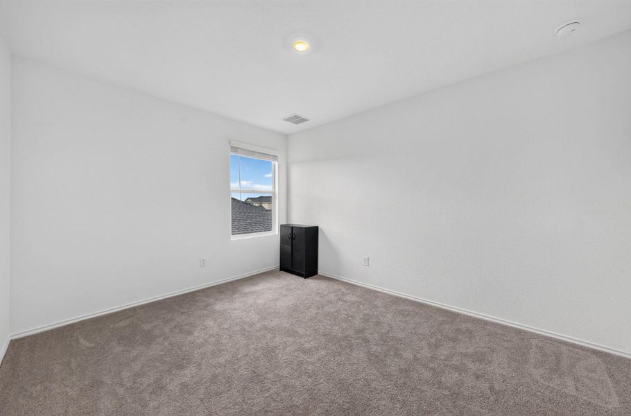 A spacious, naturally illuminated room featuring plush carpeting and an overhead light fixture. A spacious, naturally illuminated room featuring plush carpeting and an overhead light fixture.