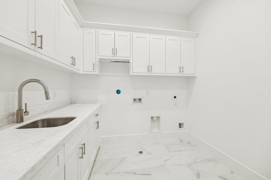 This well equipped utility room combines functionality with clean design, showcasing abundant cabinetry, a dedicated sink area, and plenty of room for laundry essentials and everyday storage. *Previous Project*