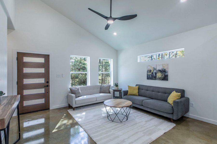 Living area featuring high vaulted ceiling, finished concrete floors, healthy amount of natural light, recessed lighting, and a ceiling fan