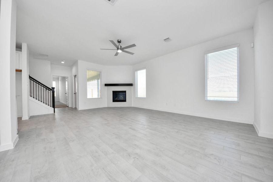 Relax and unwind in this inviting family room, illuminated by abundant natural light streaming in through tall windows, complemented by high ceilings and stunning flooring. Stay comfortable year-round with the gentle breeze from the ceiling fan, creating the perfect atmosphere for family gatherings. Sample photo of completed home with similar floor plan. Actual colors and selections may vary.