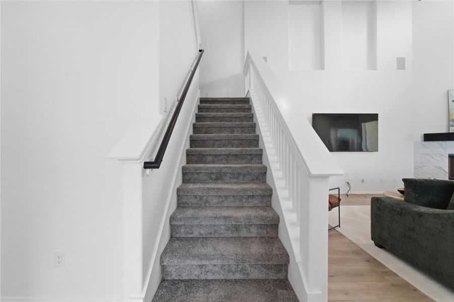 A grand carpeted staircase leads to upper levels, offering a welcoming transition to private spaces. A grand carpeted staircase leads to upper levels, offering a welcoming transition to private spaces.