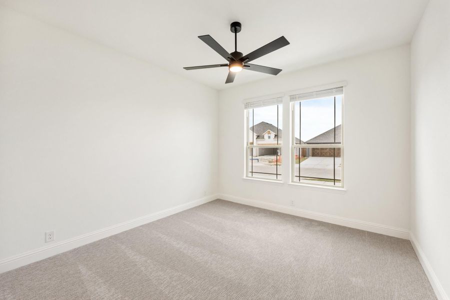 Empty bedroom with gray carpet, white walls, ceiling fan, and double window
