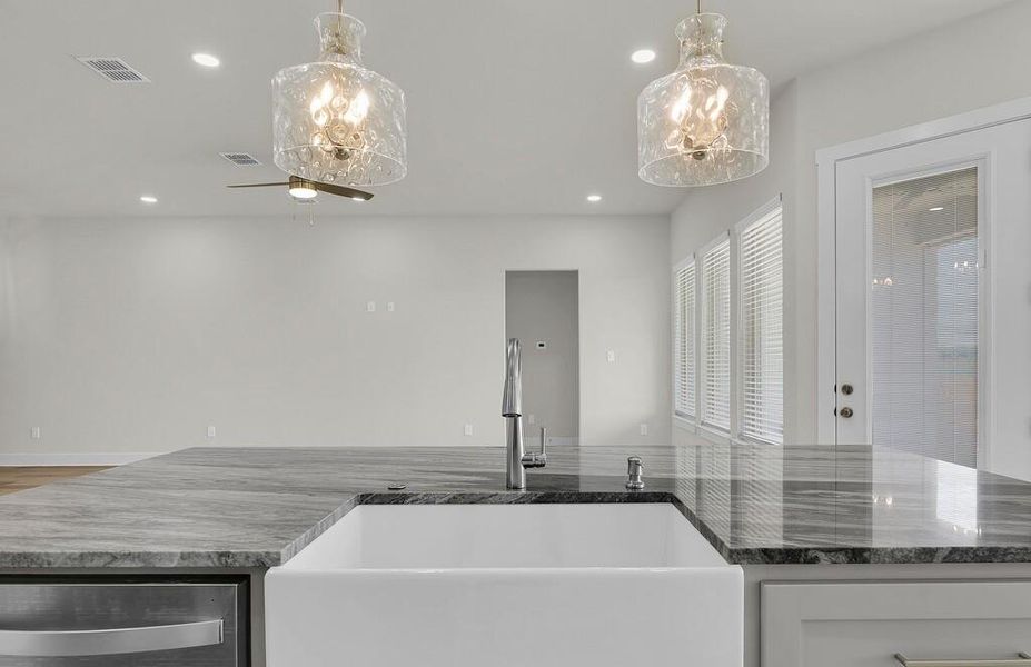 Kitchen featuring dark stone counters, stainless steel dishwasher, pendant lighting, and recessed lighting