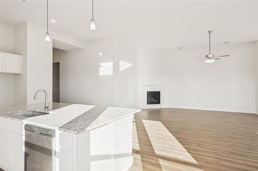 Kitchen featuring black dishwasher, sink, white cabinetry, and light wood-type flooring