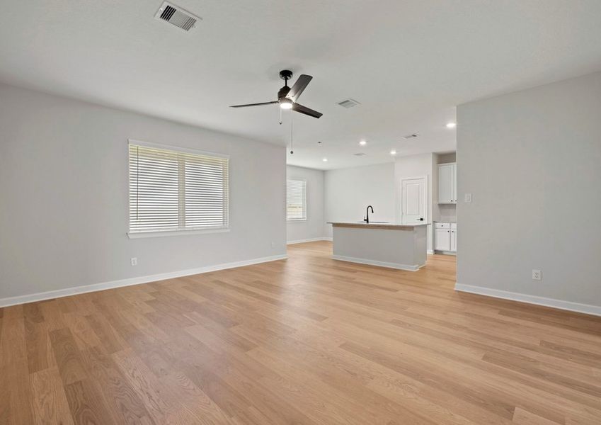 Famiy room with a large window. The dining room and kitchen are also seen in the back.