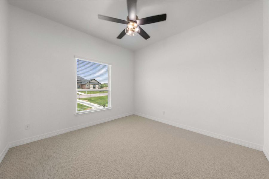 A well-lit bedroom features plush carpet, fresh paint, and a modern ceiling fan. A well-lit bedroom features plush carpet, fresh paint, and a modern ceiling fan.