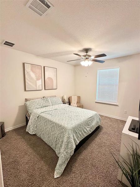 Bedroom with carpet, a textured ceiling, and a ceiling fan Bedroom with carpet, a textured ceiling, and a ceiling fan