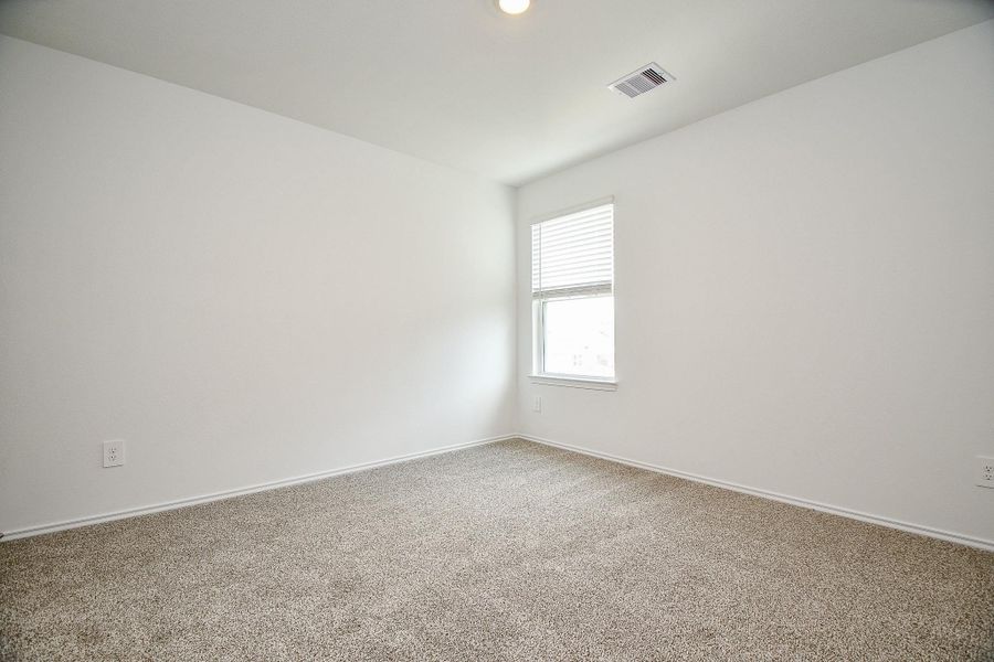 This room features a neutral color palette with plush carpet flooring and a window offering natural light. Ideal for a bedroom or home office.