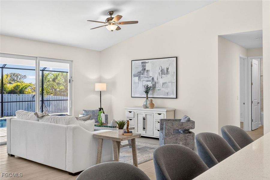 Living room with light wood-style flooring, vaulted ceiling, and ceiling fan