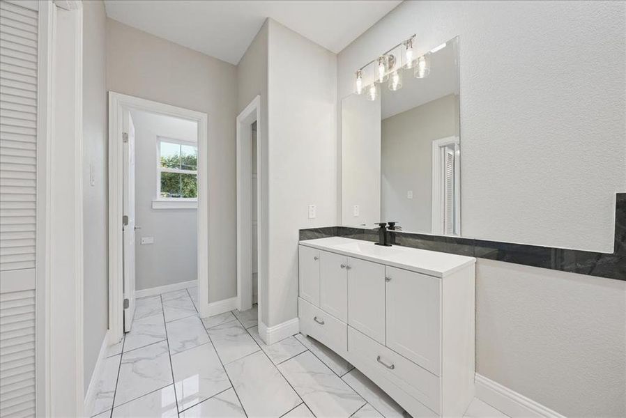 Bathroom with vanity, light marble finish flooring, and a closet