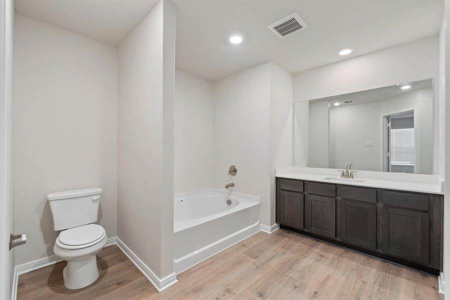 Bathroom featuring vanity, hardwood / wood-style flooring, toilet, and a washtub