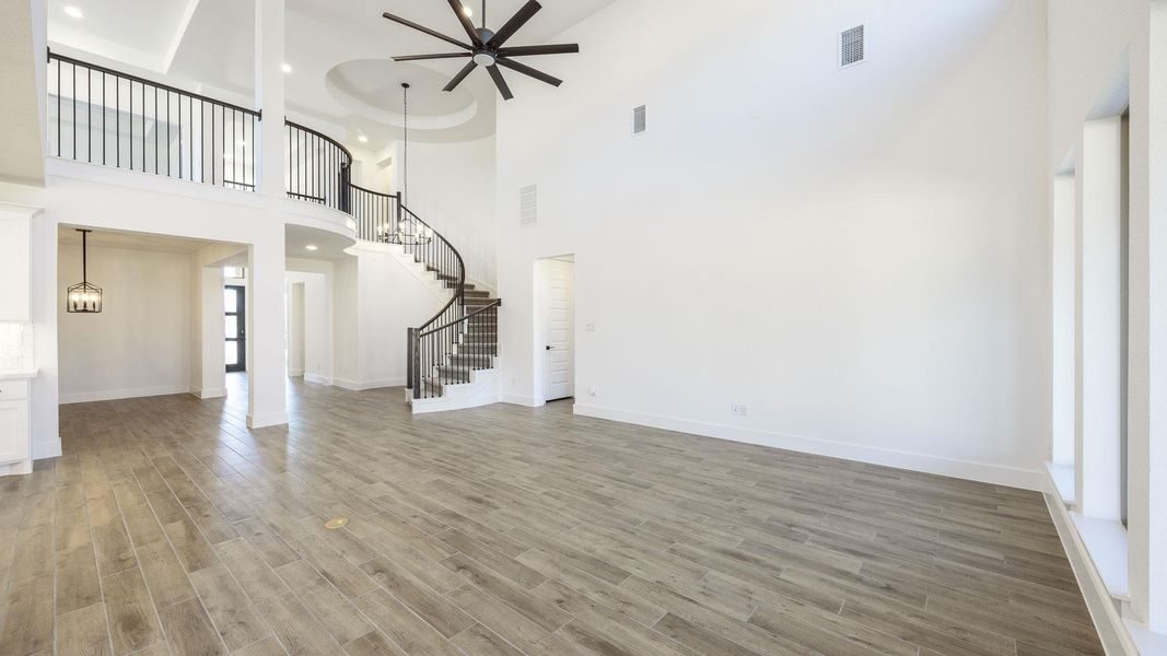 Unfurnished living room featuring stairs, light wood finished floors, a high ceiling, recessed lighting, and a chandelier Unfurnished living room featuring stairs, light wood finished floors, a high ceiling, recessed lighting, and a chandelier