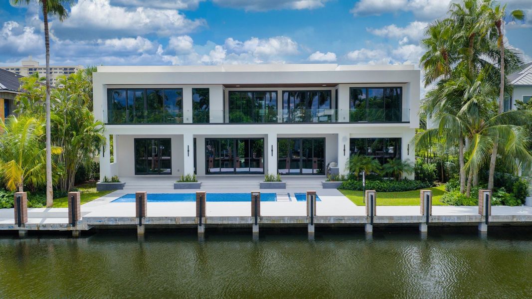 A focused aerial of a modern residence with a resort-style pool and dock directly on the canal. A focused aerial of a modern residence with a resort-style pool and dock directly on the canal.
