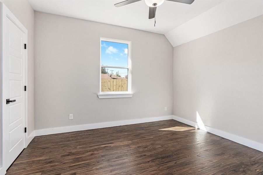 Empty room with lofted ceiling, dark wood-type flooring, and ceiling fan