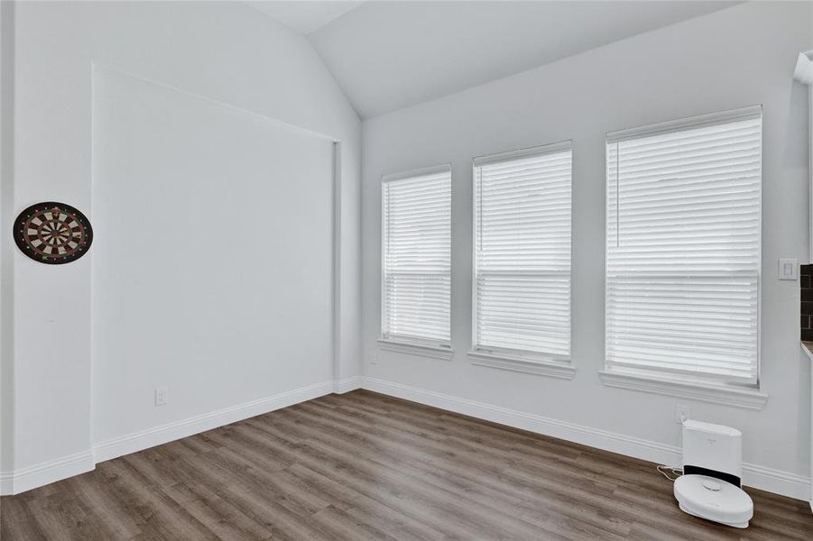 Empty room featuring dark wood finished floors and vaulted ceiling