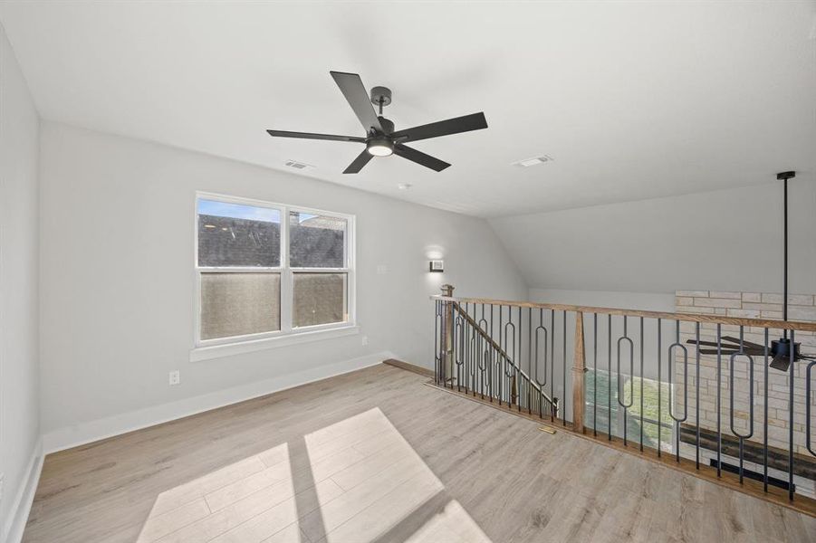 Empty room with light wood-type flooring, vaulted ceiling, and ceiling fan